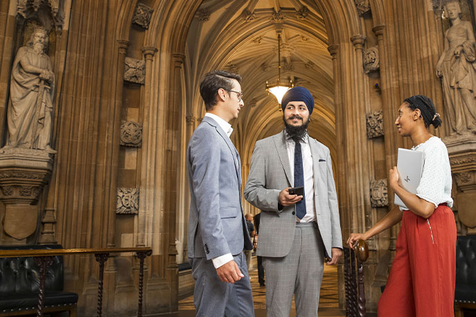 Three young people, two men and a woman, are talking. 