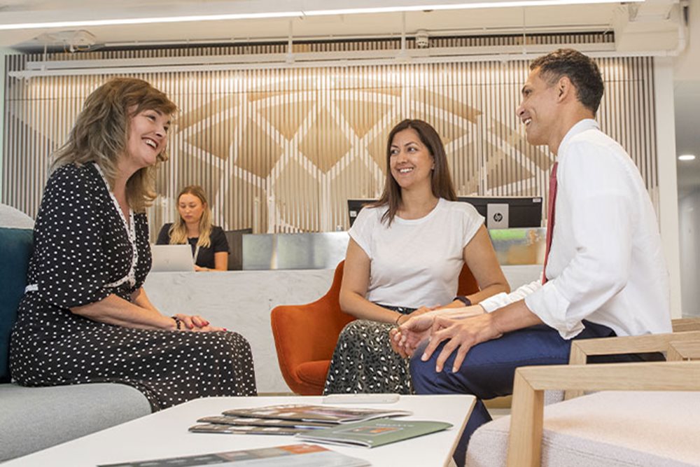 Three people are talking in an office setting.