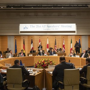 Speakers of the G7 sitting at a circular rtable under a banner  with the words The 21st G7 Speakers' Meeting