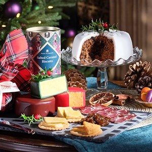 A table with Christmas decorations, Christmas cake, cheese and biscuits