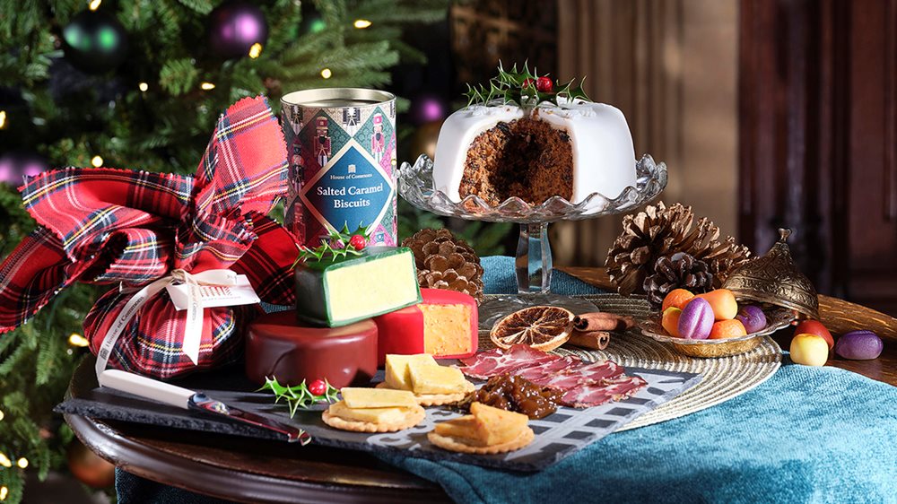 A table with Christmas decorations, Christmas cake, cheese and biscuits